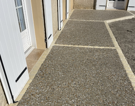 Terrasse en béton désactivé avec portes-fenêtres blanches.