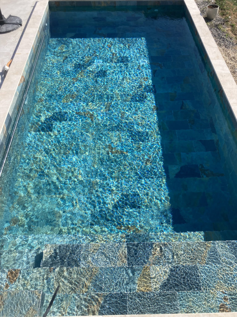 Piscine moderne avec eau cristalline et carreaux bleus.