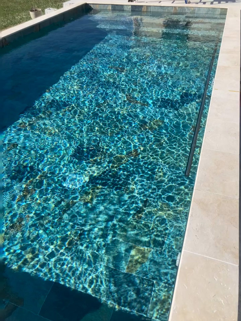 Piscine turquoise extérieure avec reflets du soleil.