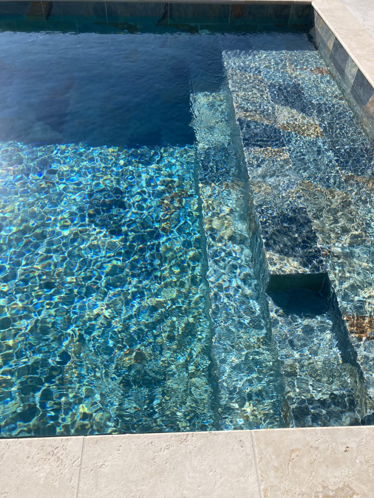 Escalier de piscine avec eau bleue cristalline.