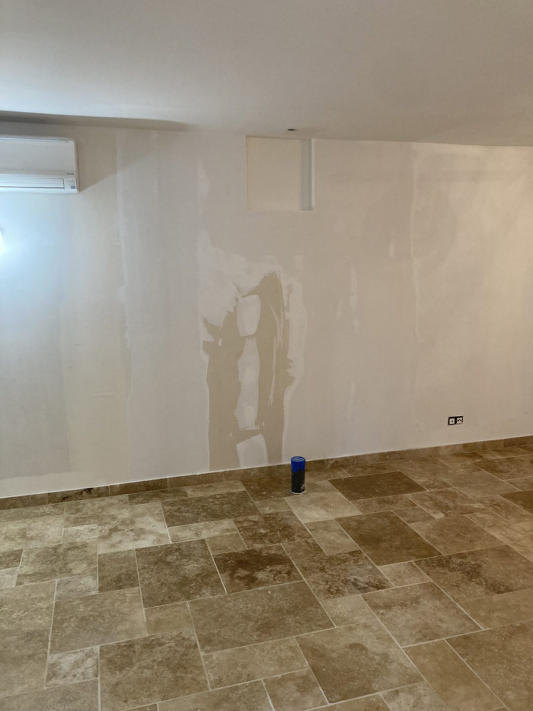 Salle avec sol carrelé et mur enduit