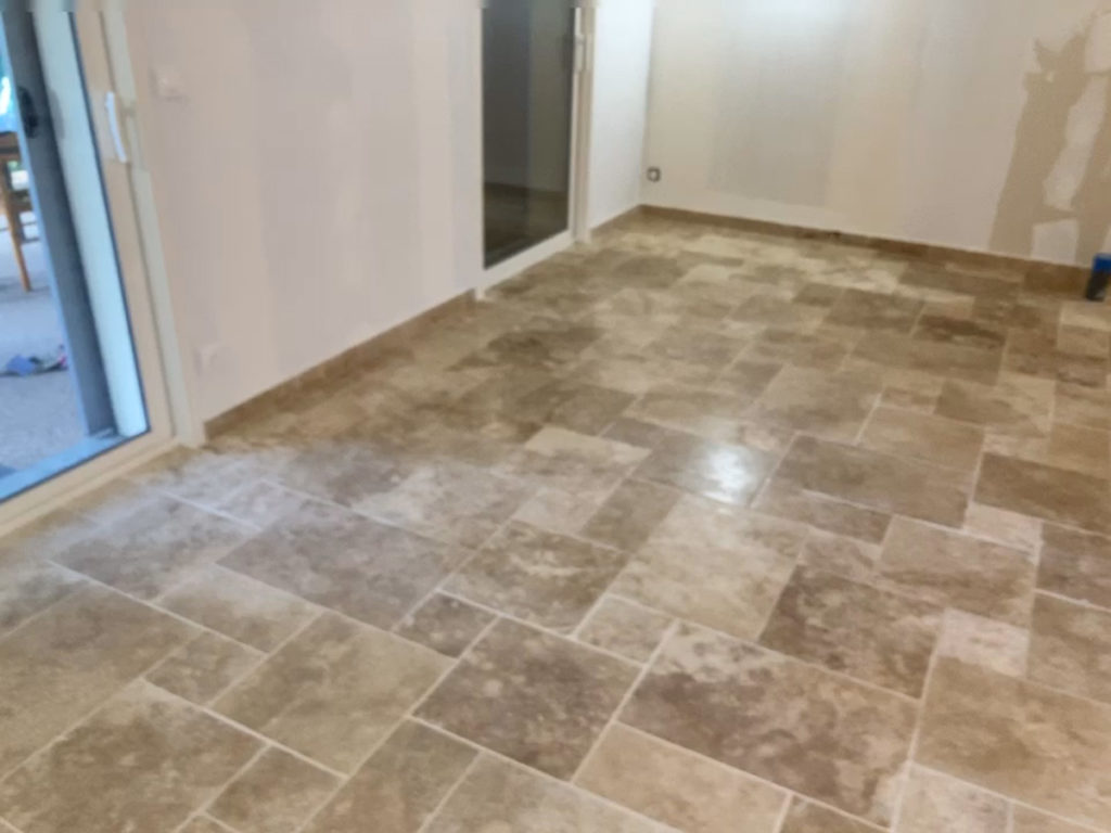 Salle avec sol en carrelage beige et portes vitrées.