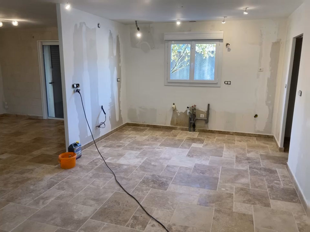 Cuisine rénovée en travaux, carrelage au sol beige.