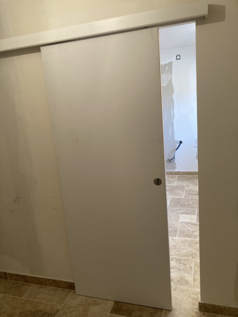 Porte coulissante blanche entre deux pièces.