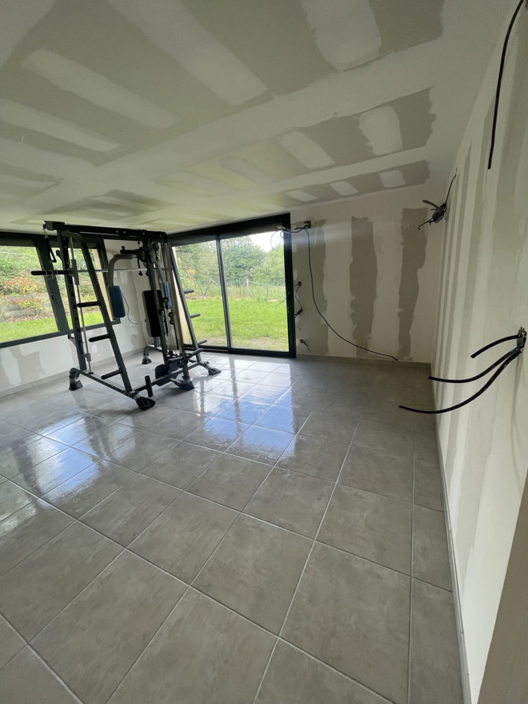 Salle de sport avec équipement et fenêtre ouverte.