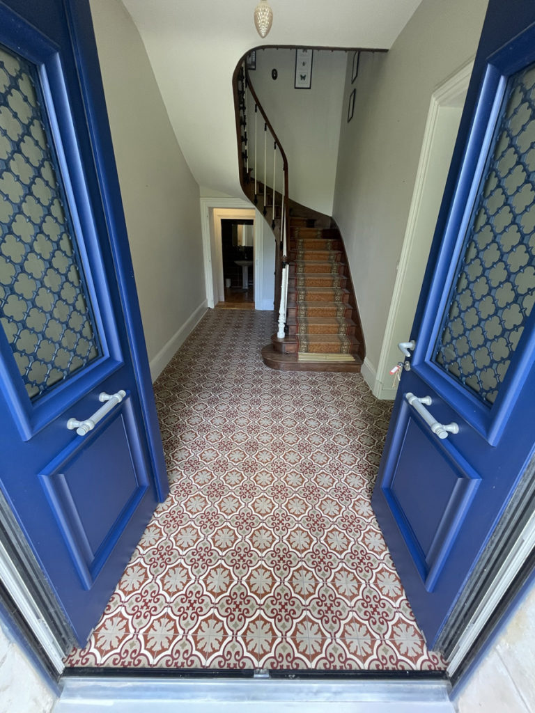 Entrée avec escalier en bois et carrelage décoratif.