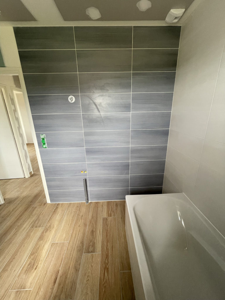 Salle de bain moderne avec carrelage et baignoire blanche.