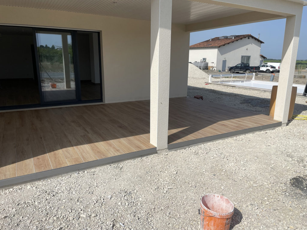 Terrasse couverte avec sol en bois, maison en construction.