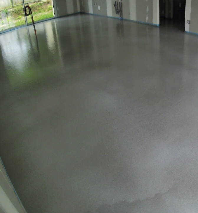 Chape fraîche dans une pièce en construction, proche extérieur.