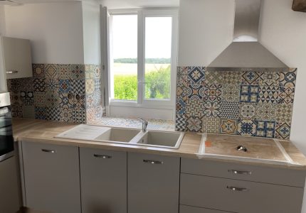 Cuisine moderne avec carrelage coloré et fenêtre.