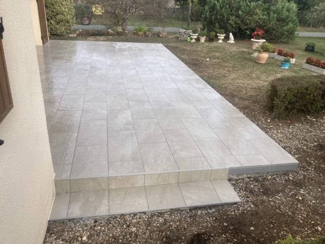 Terrasse carrelée avec jardin et plantes en pots.