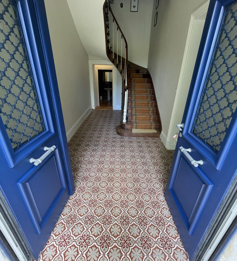 Entrée avec escalier en bois et carrelage décoratif.