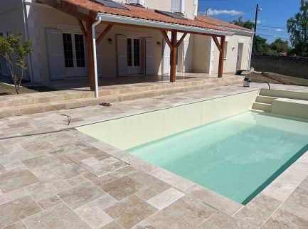 Piscine moderne devant maison en pierres.