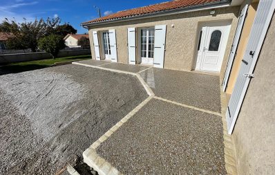 Entrée maison avec allée gravillonnée et portes blanches.