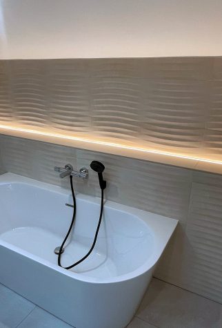 Salle de bain moderne avec baignoire et éclairage LED.