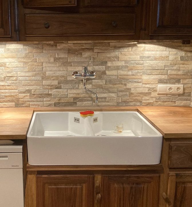 Cuisine avec évier blanc et plan de travail bois.