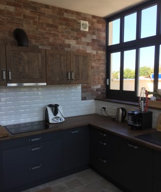 Cuisine moderne avec mur en briques et lumière naturelle.