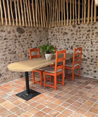 Table en bois avec chaises orange dans un patio.